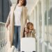 Mother and daughter travelling through an airport with a suitcase