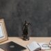 Legal documents, books and a justice statue on a lawyer's desk